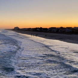 a beach with waves and buildings in the background